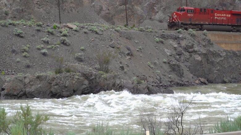 A red CN Rail train passes over the swollen Thompson River near Spences Bridge, B.C., on Tuesday.