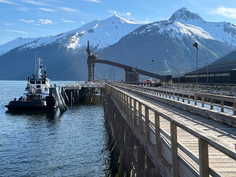 An industrial dock on the ocean with mountains visible across the water.