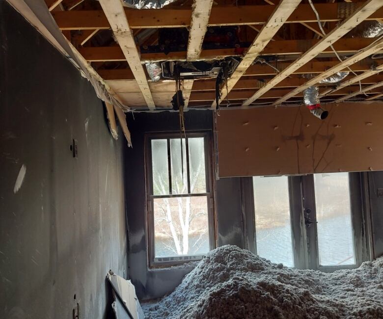 Exposed wooden ceiling beams and a pile of ash on the floor.