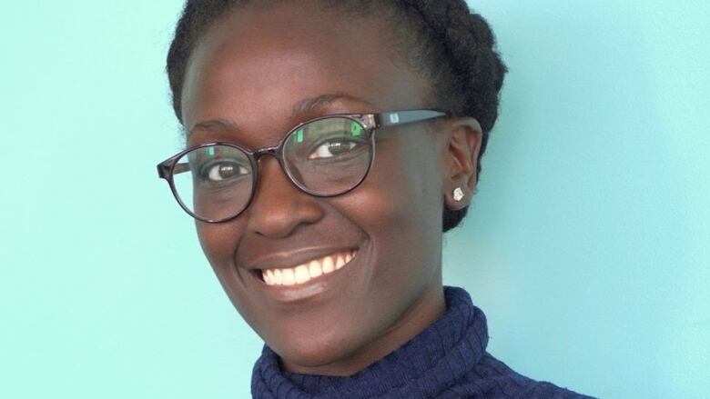 A smiling woman wearing glasses looks at the camera.