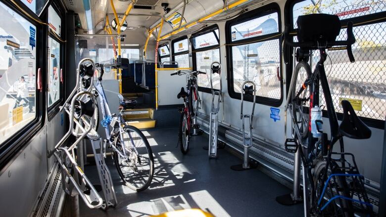 A sunny bus interior with multiple bicycles clasped to harnesses.