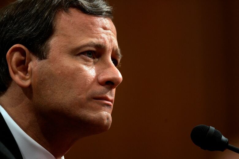 A closeup of a man sitting at a microphone.