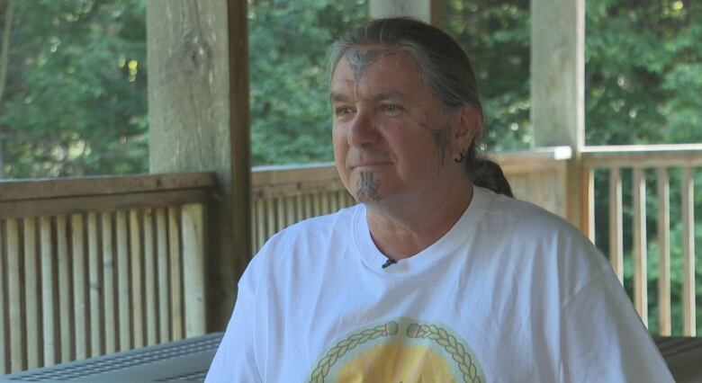 man with face tatooes and long, greying hair pulled back into a ponytail.