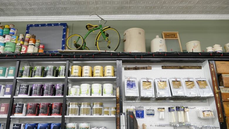 Shelves of paint and painting supplies line a wall.