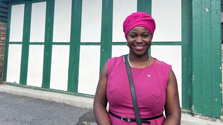 A woman stands smiling in front a chalet in a park.  