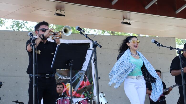 A man and woman in a band perform on a stage. 