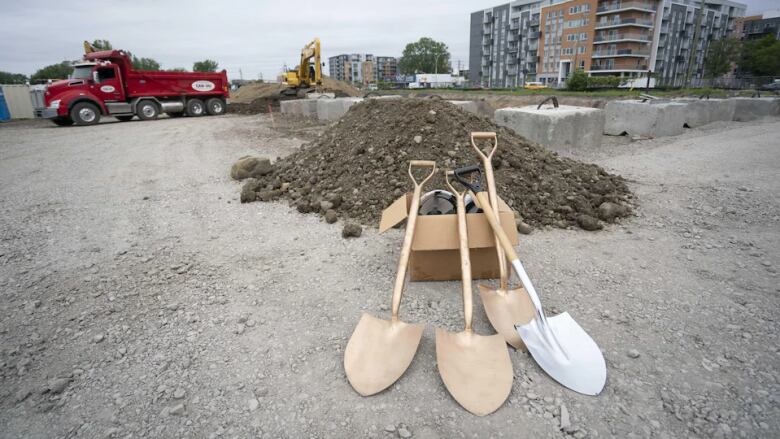 Four shovels are placed on a box on a construction site. 