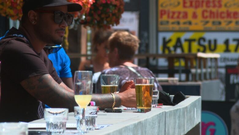 A man sits on a patio with drinks on it. 