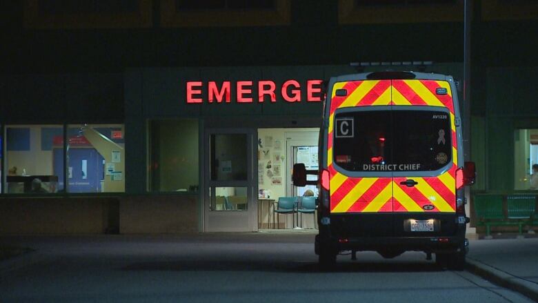 A van with yellow and red stripes is parked in front of a sign that reads emergency. 