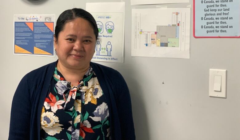 A woman standing in an office space smiles at the camera.