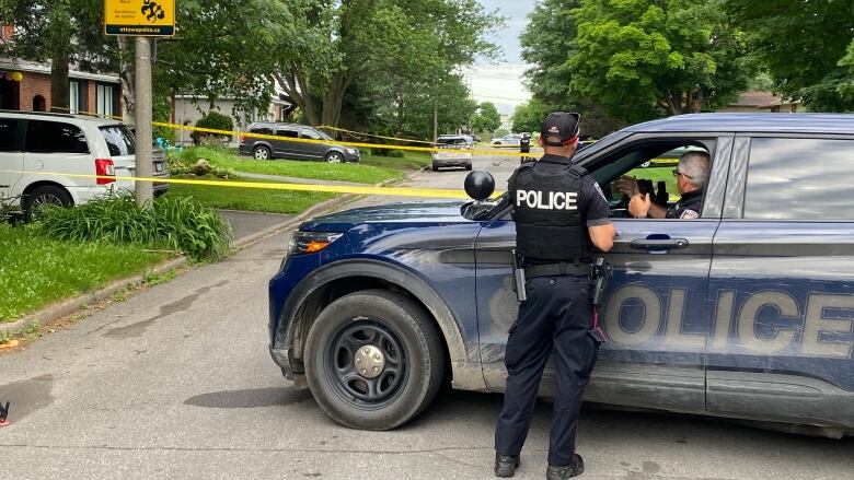 Police watch over a taped-off section of a residential street.