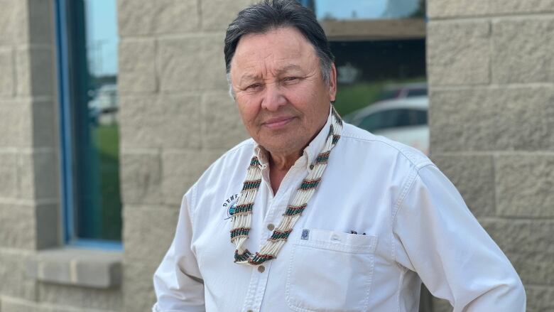 A portrait of a man standing outside with his hands on his hips in front of a building.