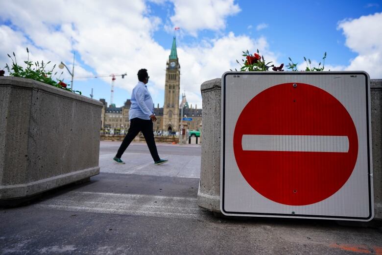 Someone passes by a road closure sign in front of Parliament Hill.