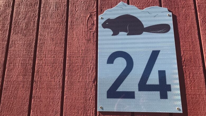 A sign with the number 24 and a graphic of a beaver on top, on red wood.