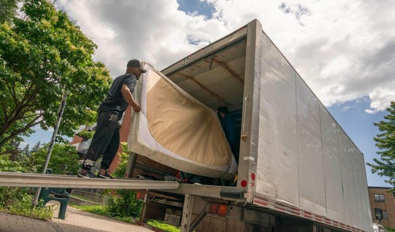 A man loads a mattress into a moving truck.