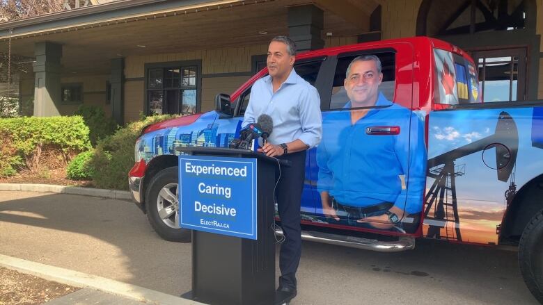 A man standing at a podium in front of a truck.