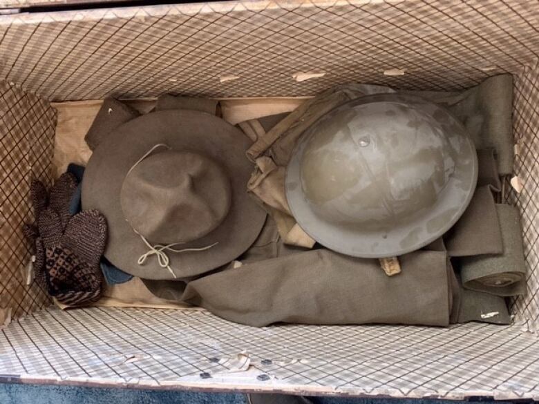 A trunk containing mittens, hat, helmet and uniform.