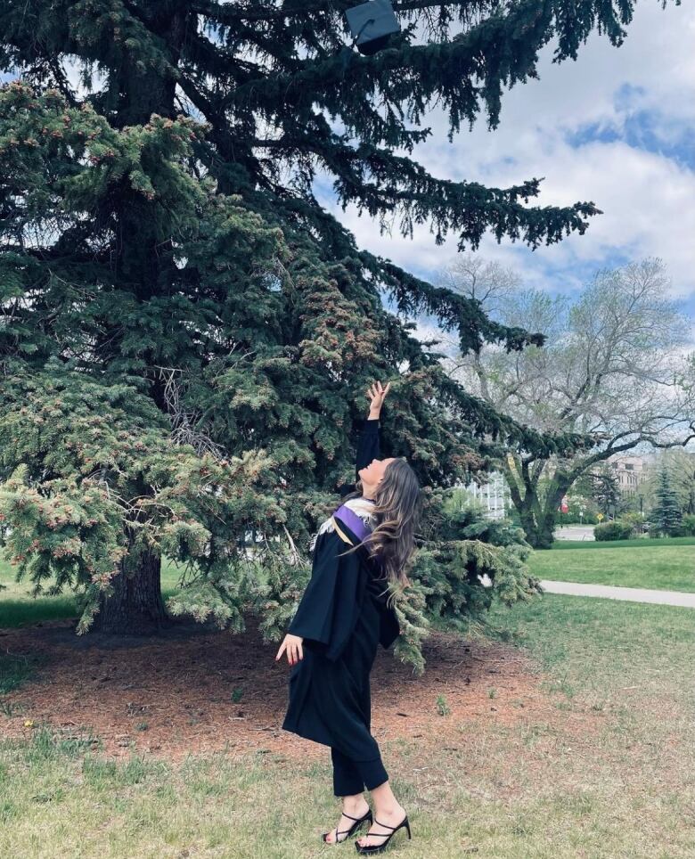 A woman outside throwing her graduation cap in the air.