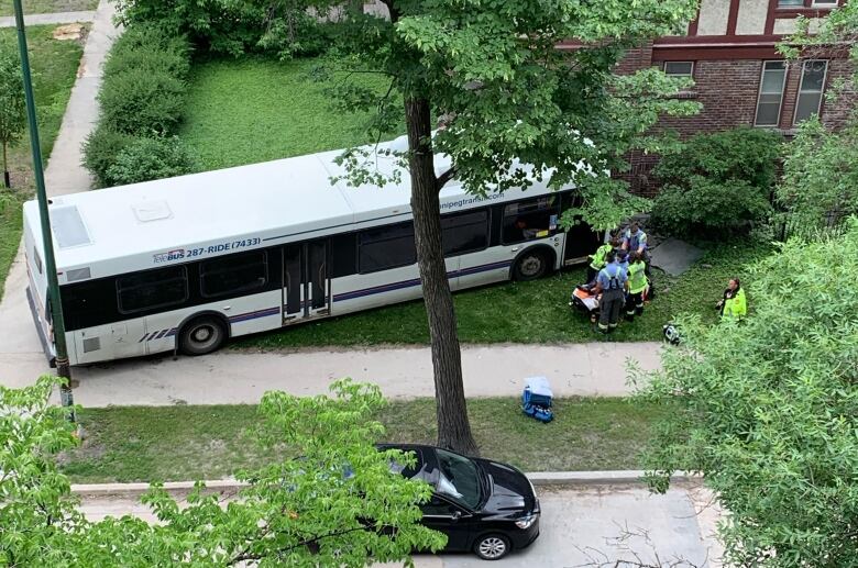 An overhead photo shows a bus crashed into the side of a red brick building.