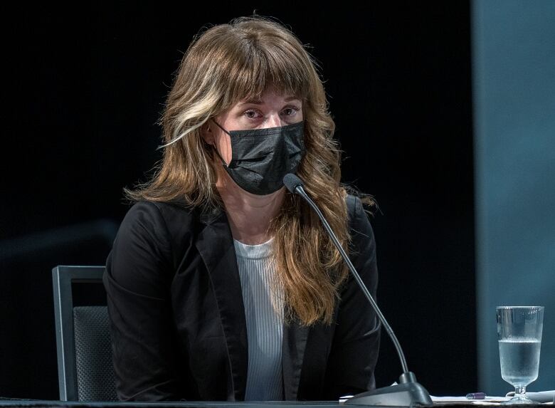 A woman is seen sitting in front of a microphone at the Mass Casualty Commission inquiry.