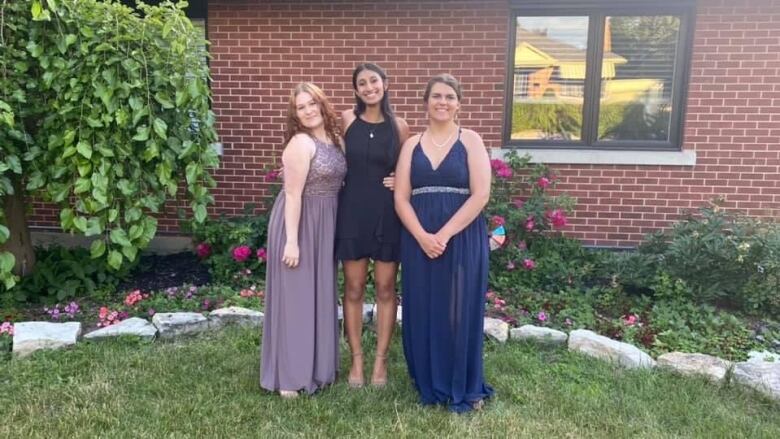 Three teen girls pose for a photo.