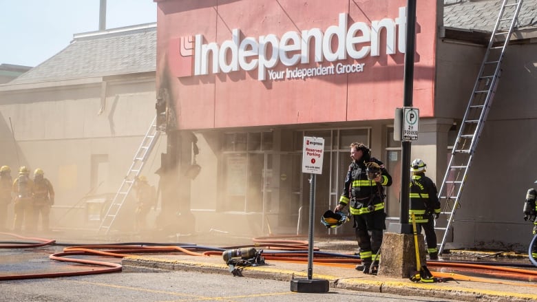 fire fighters standing in smoke billowing from entry of independent grocer in kentville