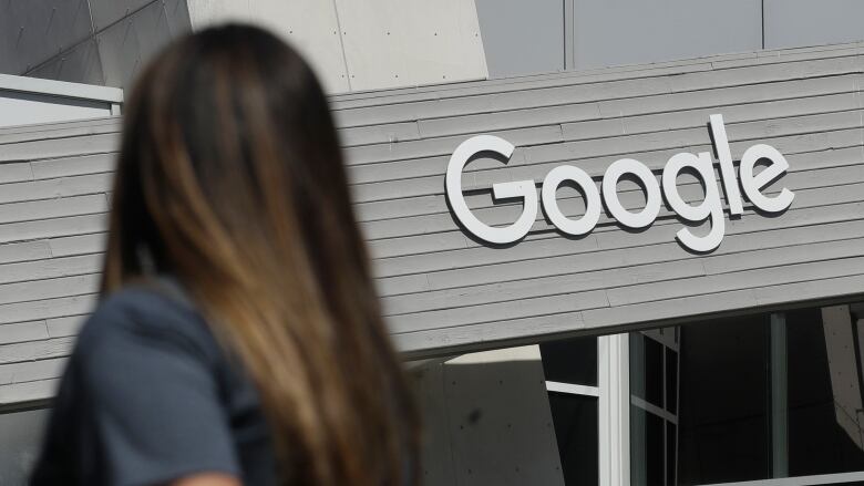 A woman walks below a Google sign on the company's campus in Mountain View, Calif., in this Sept. 24, 2019, file photo.