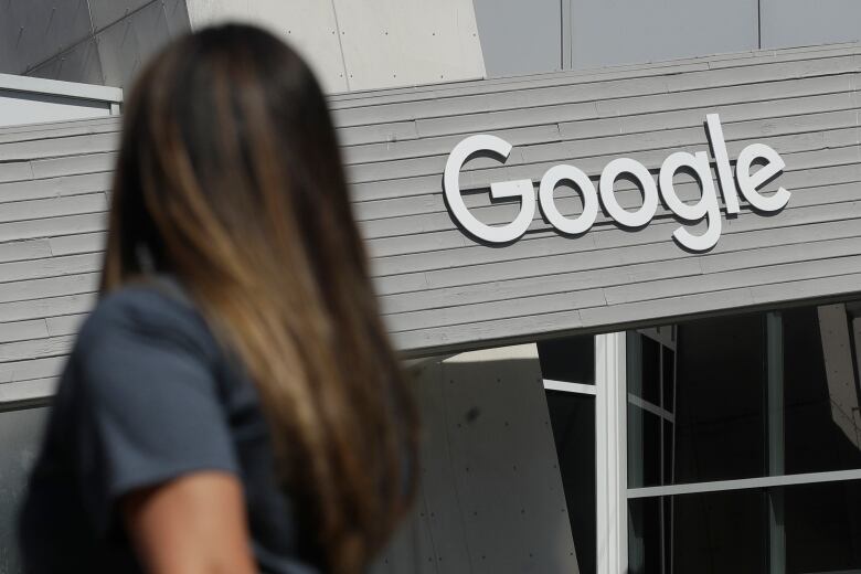 A woman walks below a Google sign on the company's campus in Mountain View, Calif., in this Sept. 24, 2019, file photo.