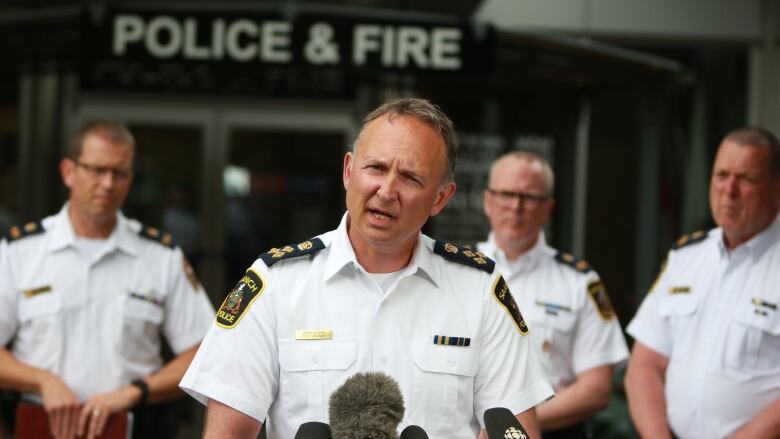 A police chief speaks at a podium with other police officers behind him.