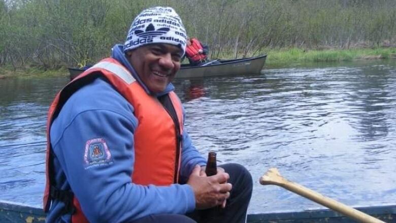 A man on a canoe, wearing life jacket, smiling