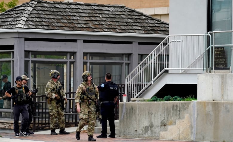 Five police officers survey a downtown area. 