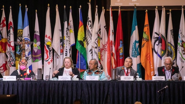 First Nations leader sit together on stage.