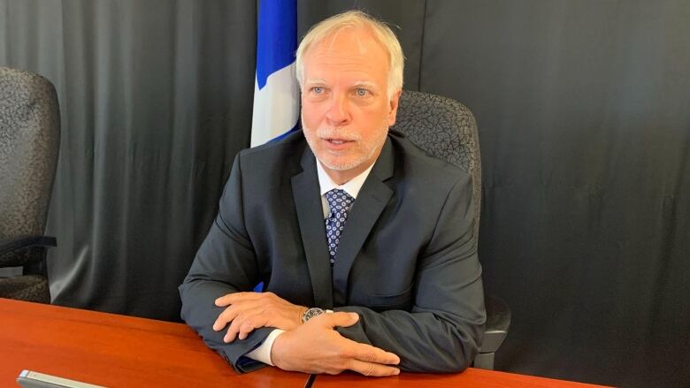 A man sitting at a table during a news conference.