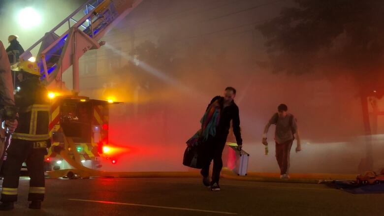 Residents of the 100-block of East Hastings Street leave with their belongings after a major fire broke out in a neighbouring building, the Downtown Eastside Street Church, around 9:30 p.m. on Wednesday, July 6, 2022.