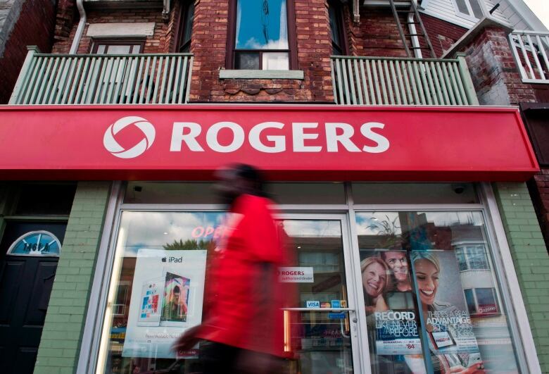 A person walks by a Rogers sign