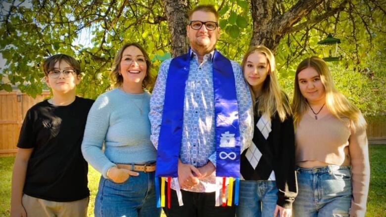 A family poses for a photo in front of a tree.