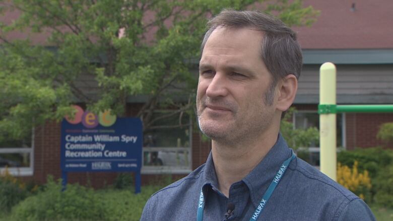 A man stands at a playground in front of a community centre.