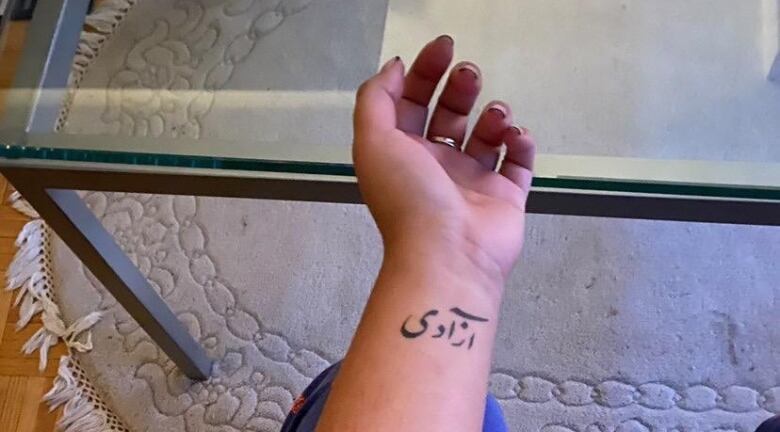 An Urdu script is seen tattooed on a forearm.