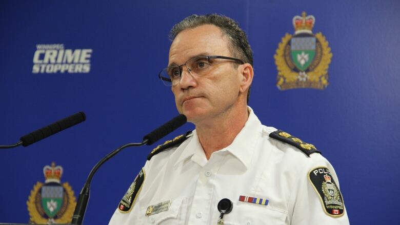 A man in a police uniform speaks at a podium.