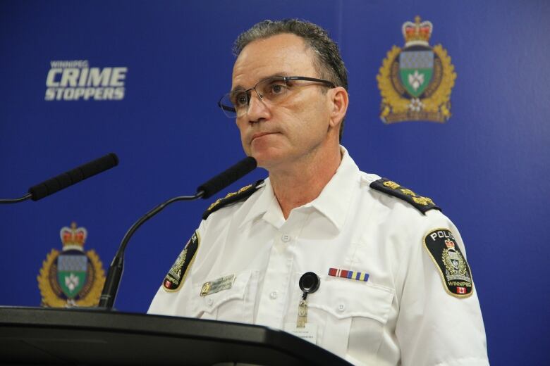 A man in a police uniform speaks at a podium.