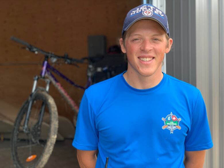 A person smiling in front of a bike shed.