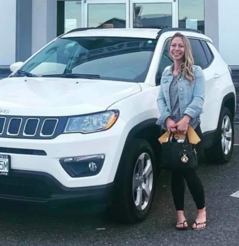 A blonde woman stands beside a white SUV.