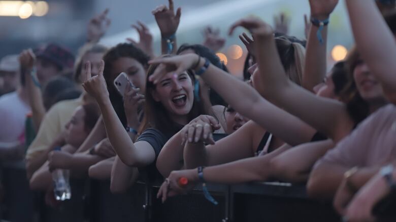 Young people smiling, waving their hands, holding water bottles and phones.