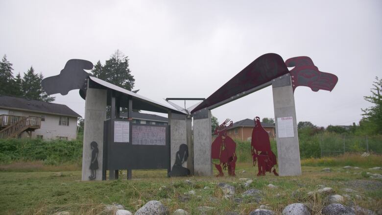 A monument featuring metal work depicting children and Indigenous designs. 