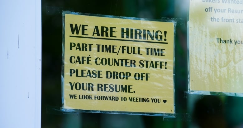 A hiring sign in a business window.