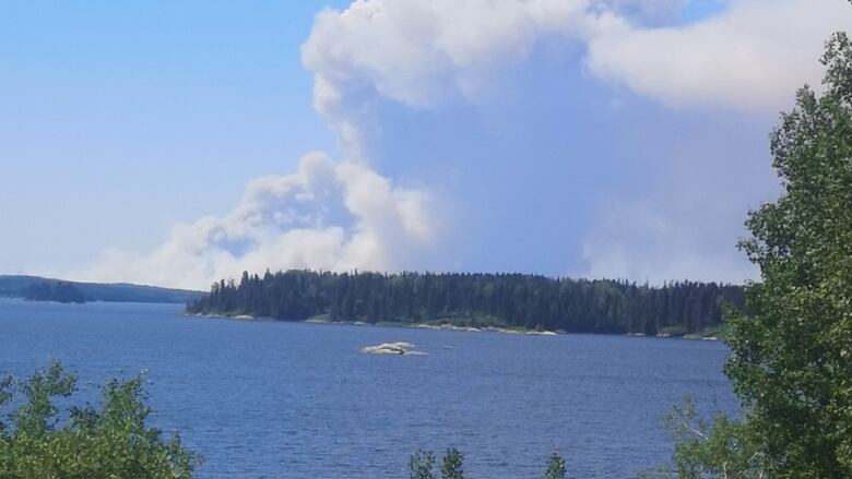 Billowing smoke on the horizon on the other side of a body of water.