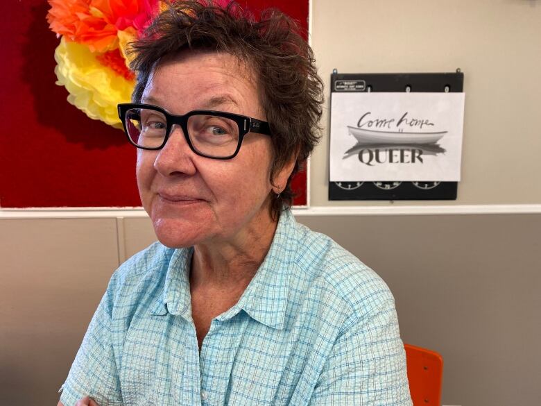 A woman wearing glasses sits at a table.