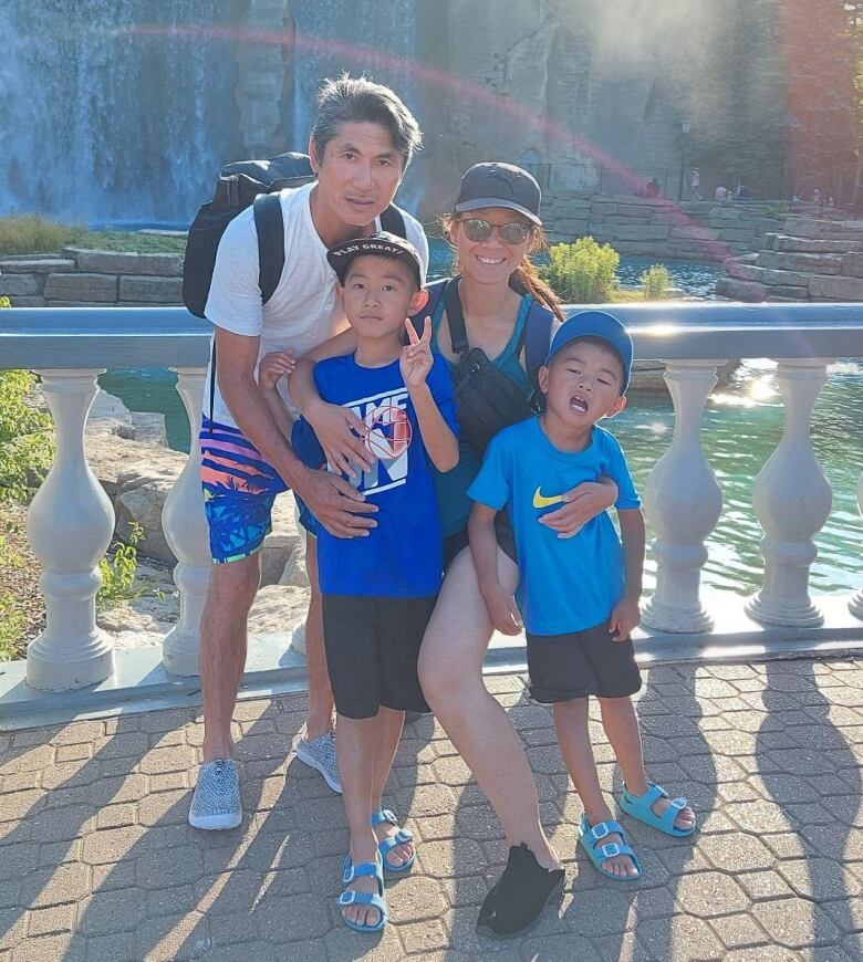 A father, mother and their two young sons pose in front of a cascade.