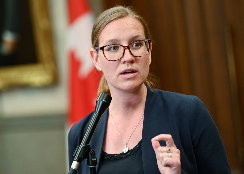 Woman stands before microphone in the House of Commons on Parliament Hill.