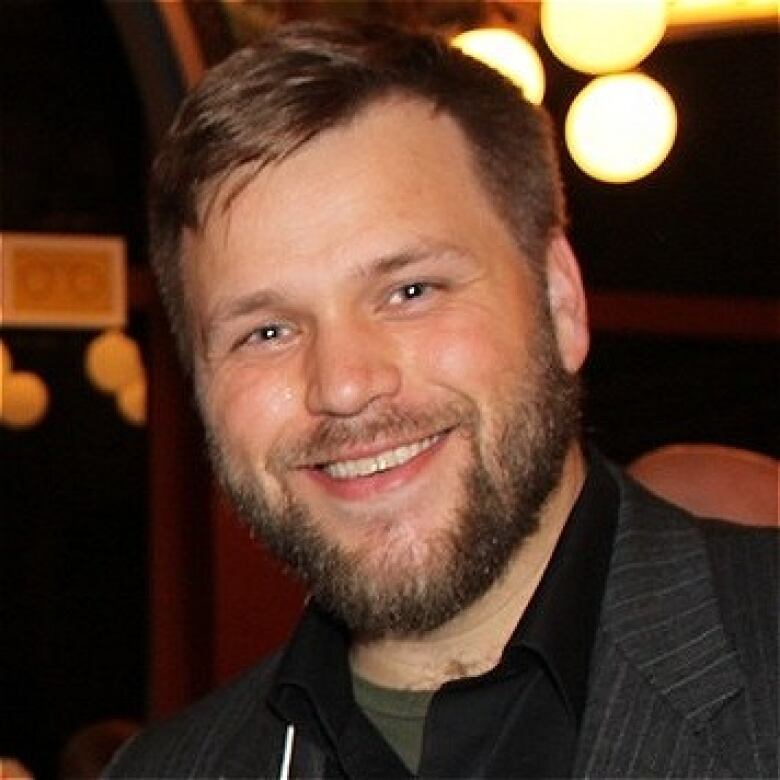 A headshot of a smiling man.